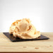 Glace saveur pêche posée, texture juteuse avec morceaux de fruit visibles.