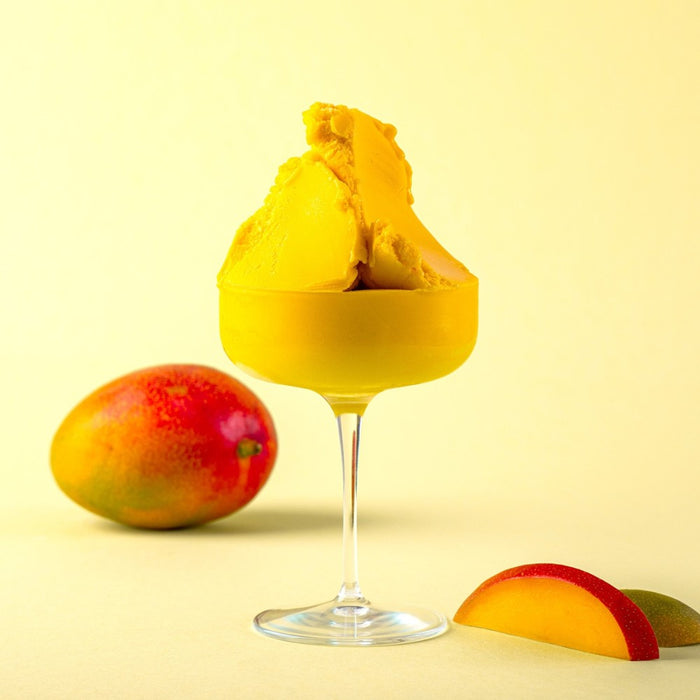 Glace à la mangue dans un verre, texture lisse et couleur jaune intense.